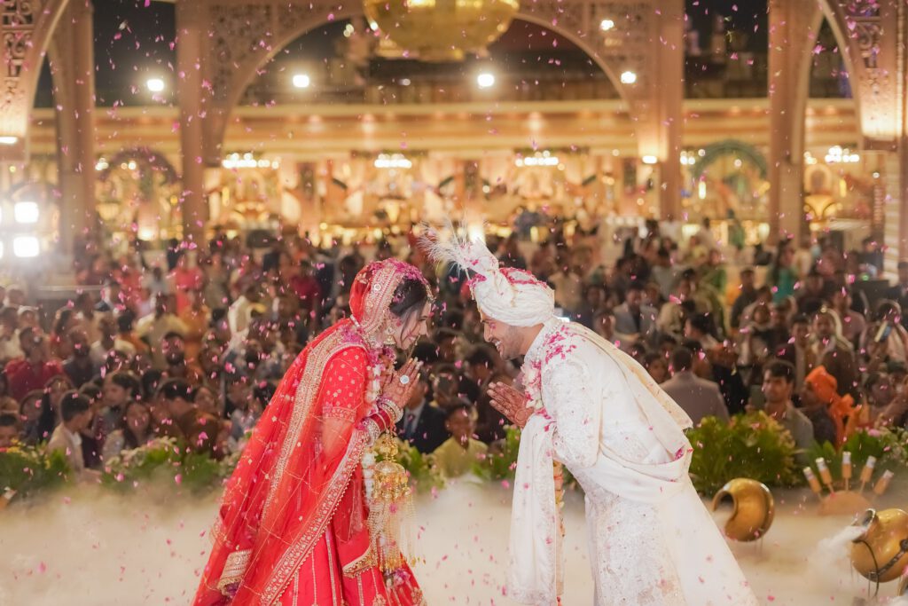 Bride and groom in traditional attire celebrating their wedding with a bow in Delhi, India.
